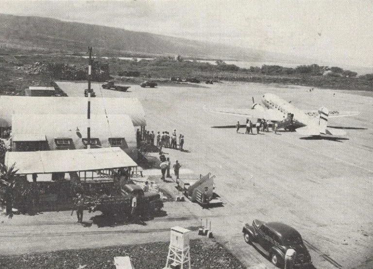 Vintage black and white picture of the airport with people walking to board the plane.